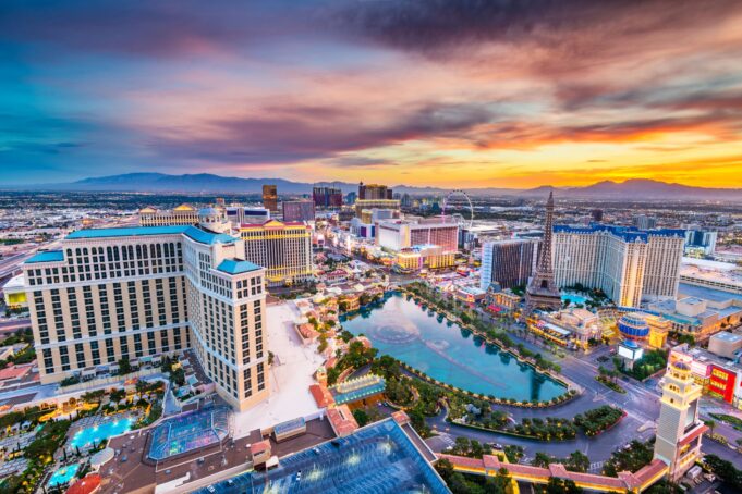 This image captures a vibrant view of the Las Vegas Strip at dusk, showcasing iconic hotels, casinos, and attractions under a colorful sunset sky.